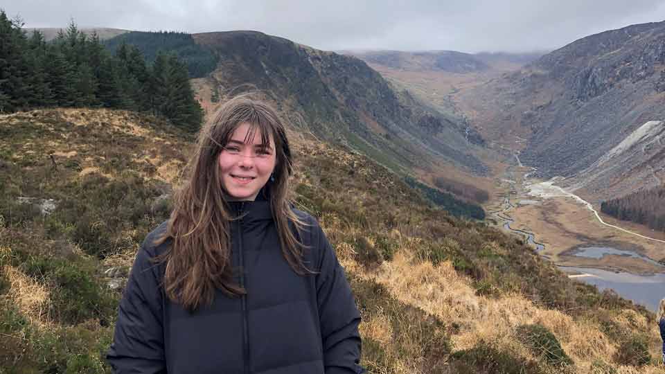 Lina steht vor einer bergigen irischen Landschaft